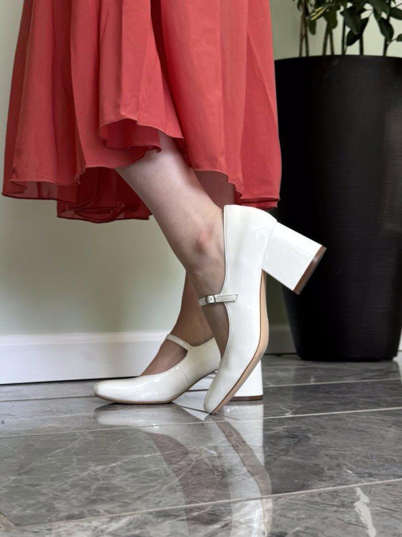 White shoes worn with a red skirt on a tiled floor.#color_white