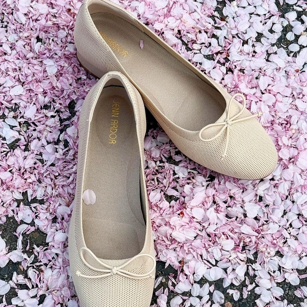 Beige flats with a bow on a bed of pink flower petals#color_beige