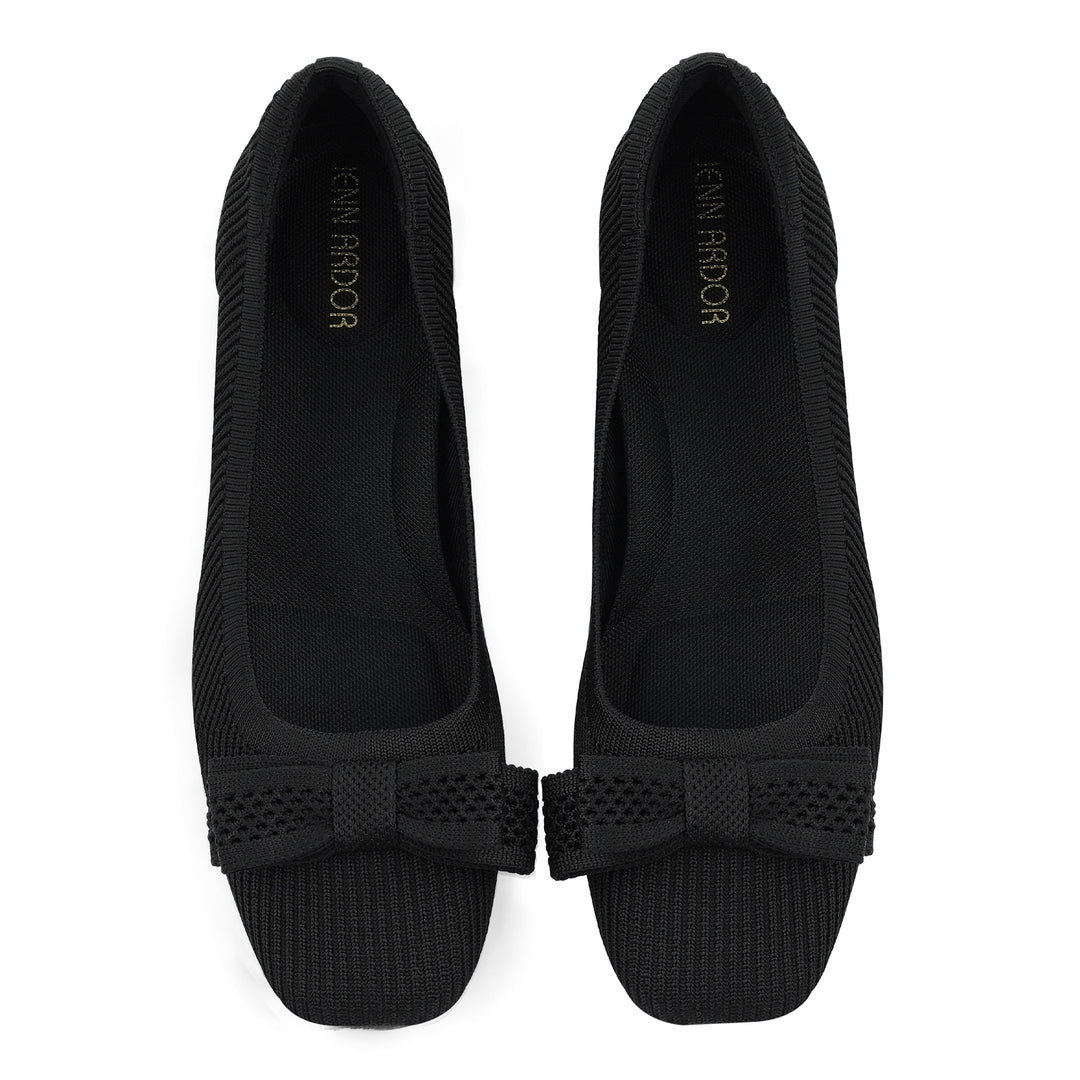 Pair of black flat shoes with a bow detail on a white background#color_black