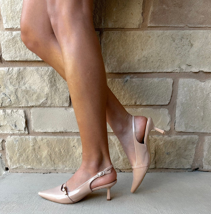 Person wearing pink high-heeled shoes against a stone wall.#color_beige