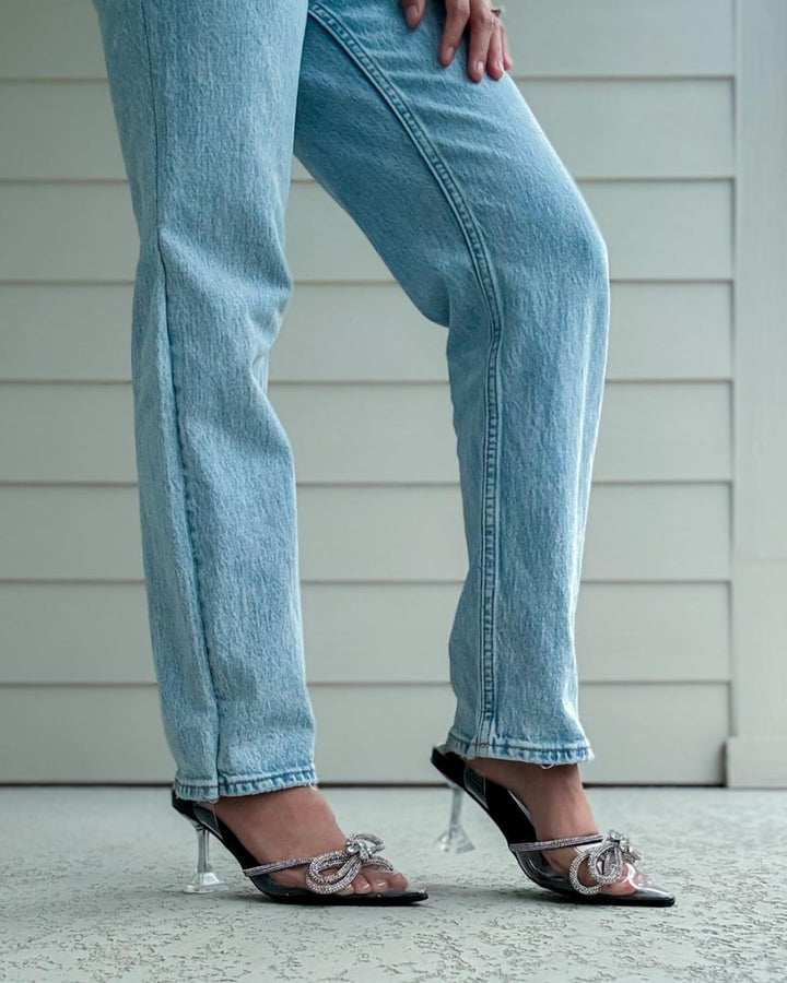 Person wearing light blue jeans and high-heeled shoes on a neutral background#color_black