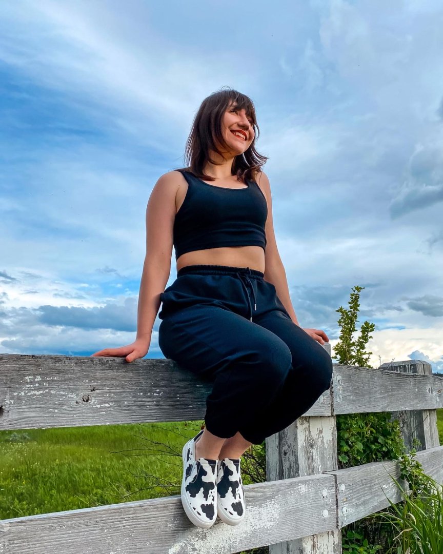 Woman sitting on a wooden fence with a scenic background#color_cow
