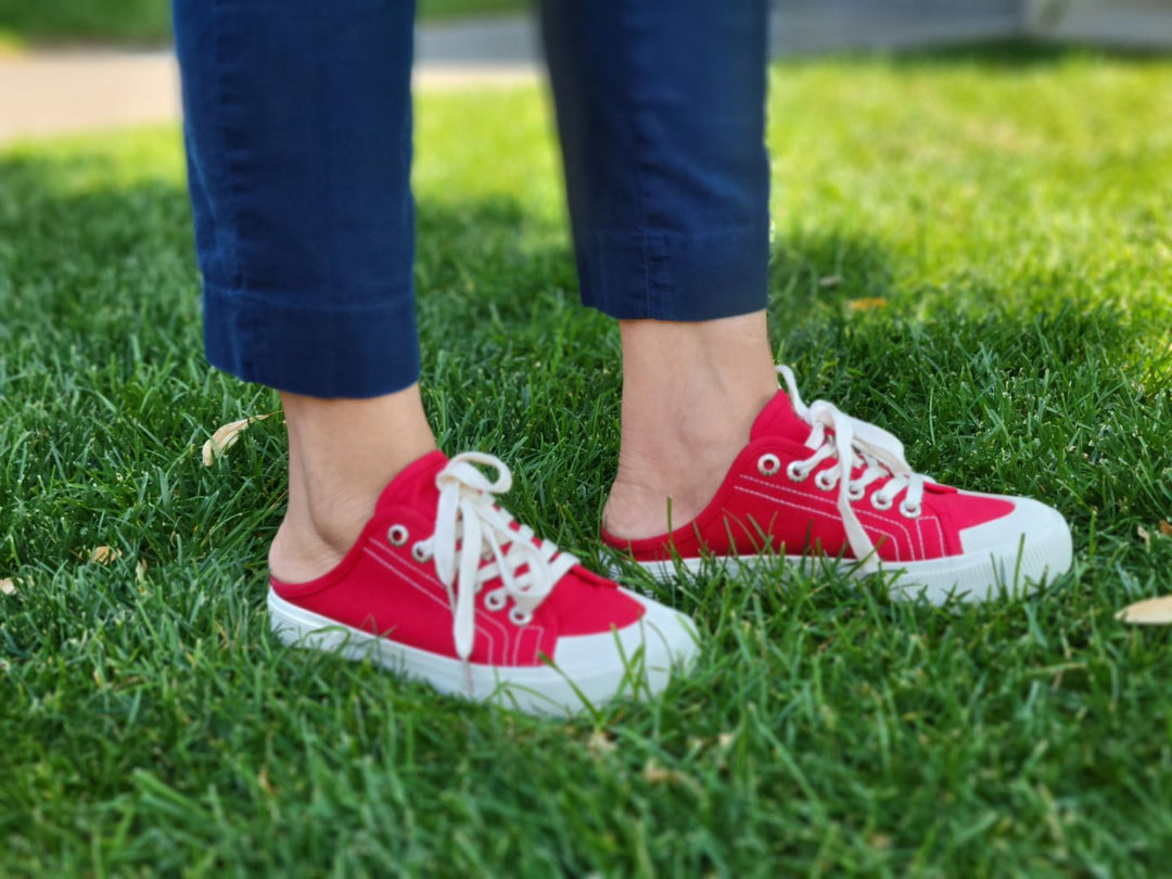 Red sneakers with white soles worn on grass#color_red