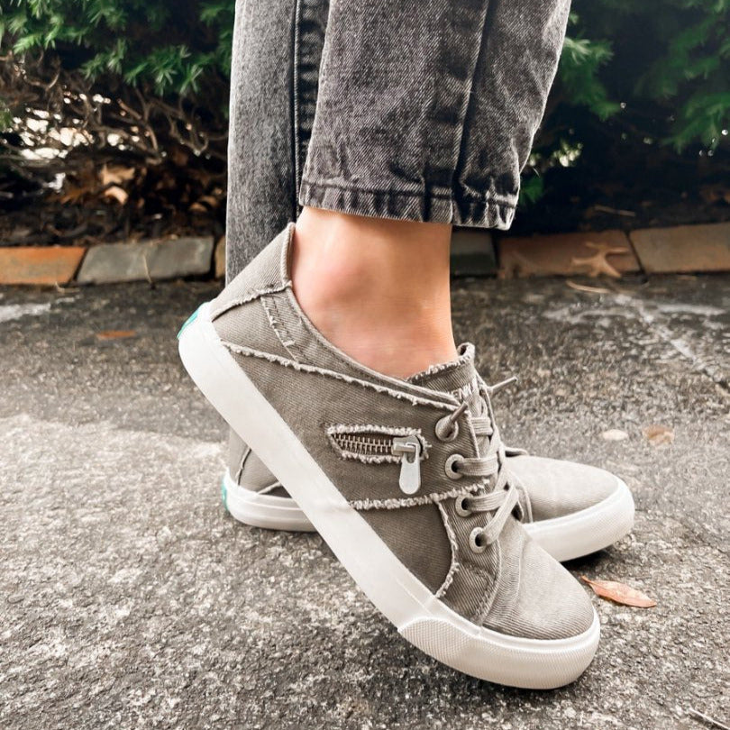 Person wearing gray high-top sneakers with white soles on a pavement background#color_grey
