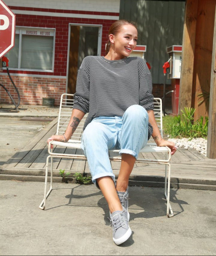 Woman sitting on a chair in front of a building with signs.#color_light-grey