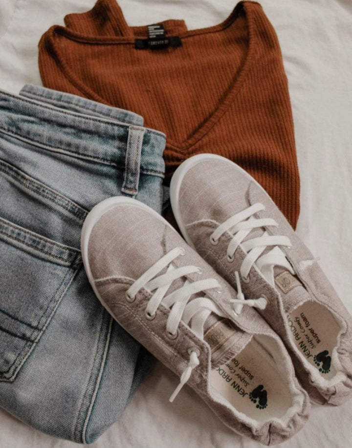 Brown ribbed sweater, light blue jeans, and beige sneakers on a white surface#color_light-grey