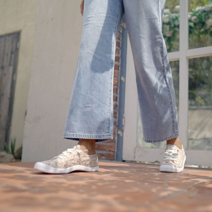 Person wearing light blue jeans and white sneakers standing on a tiled floor.#color_flower