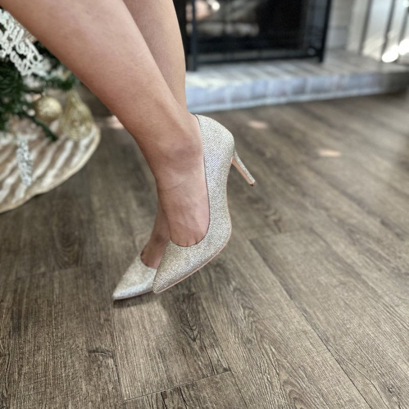 Person wearing glittery high-heeled shoes on a wooden floor#color_gold