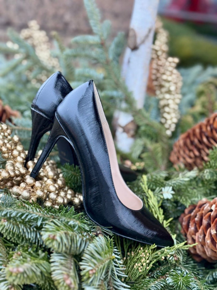 Black high-heeled shoes on a decorative background with greenery and pinecones#color_p-black